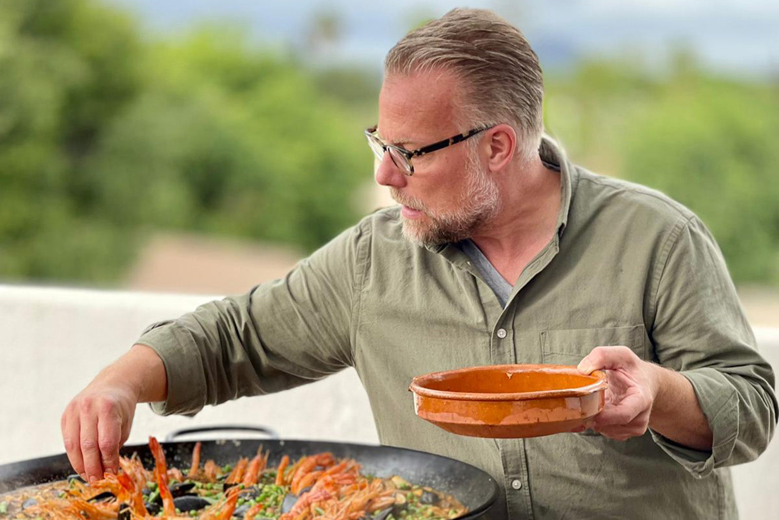 Privatkoch auf Mallorca bereitet frische Paella beim Catering Event im Freien zu